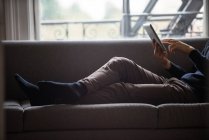 Homme utilisant une tablette numérique dans le salon à la maison — Photo de stock