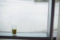 Copo de suco mantido na soleira da janela em casa — Fotografia de Stock