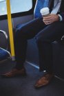 Низька секція бізнесмена, що тримає одноразову чашку кави під час подорожі в автобусі — стокове фото