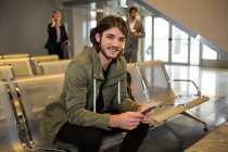 Uomo con passaporto e carta d'imbarco seduto in sala d'attesa al terminal dell'aeroporto — Foto stock