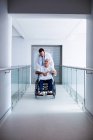 Médico interagindo com paciente sênior do sexo masculino em uma cadeira de rodas na passagem — Fotografia de Stock