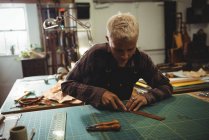 Artisanat attentif coupant un morceau de cuir en atelier — Photo de stock