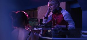 Female dj playing music while interacting with woman at bar — Stock Photo