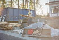 Trabalhador da construção civil que transporta madeira no estaleiro — Fotografia de Stock