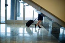 Commuter walking at airport terminal with luggage in airport terminal — Stock Photo