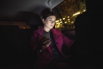 Belle femme d'affaires utilisant tablette numérique et téléphone dans la voiture — Photo de stock