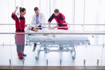 Лікарі вивчають пацієнта в коридорі в лікарні — стокове фото