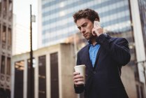 Empresário falando no celular e segurando café na rua — Fotografia de Stock