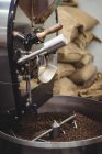 Coffee beans being grinded in coffee grinding machine in coffee shop — Stock Photo