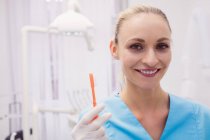Portrait d'une dentiste tenant une brosse à dents dans une clinique dentaire — Photo de stock