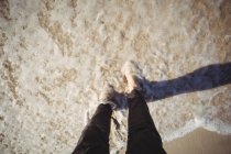 Niedriger Abschnitt einer Frau, die am Strand auf dem Wasser geht — Stockfoto