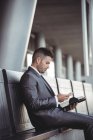 Бізнесмен з щоденником за допомогою мобільного телефону сидячи на лавці в офісному кампусі — стокове фото