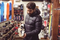 Hombre guapo seleccionando fijaciones de esquí en una tienda - foto de stock