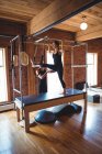 Instrutor ajudando a mulher enquanto pratica pilates no estúdio de fitness — Fotografia de Stock