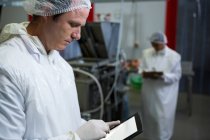 Macellaio maschio che utilizza tablet digitale in fabbrica di carne — Foto stock