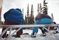 Visão traseira do casal sentado no banco na montanha coberta de neve — Fotografia de Stock