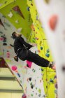 Homme pratiquant l'escalade sur mur d'escalade artificiel dans la salle de gym — Photo de stock