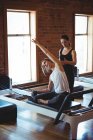 Treinador assistindo uma mulher enquanto pratica pilates no estúdio de fitness — Fotografia de Stock