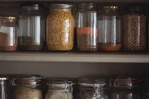 Крупный план различных бобов и чечевицы в банках на полке кухни — стоковое фото