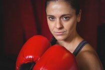 Confident female boxer performing boxing stance in fitness studio — Stock Photo