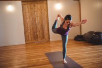 Женщина балансирует во время занятий йогой в фитнес-студии — стоковое фото