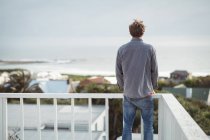 Rear view of man standing on balcony and looking at view — Stock Photo