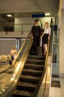 Pilot und Mitarbeiter unterhalten sich auf der Rolltreppe im Flughafenterminal — Stockfoto