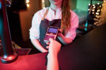 Клієнт здійснює оплату кредитною карткою за лічильником в барі — стокове фото