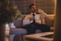 Бізнесмен розмовляє на мобільному телефоні, маючи каву вдома — стокове фото