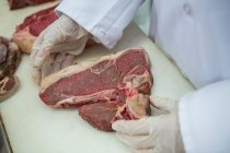 Gros plan d'un boucher détenant de la viande dans une usine de viande — Photo de stock