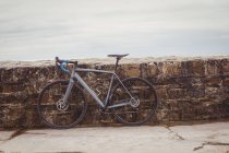 Bicicleta estacionada contra la pared costera de mala calidad - foto de stock