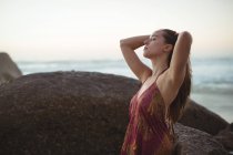 Блаженна жінка стоїть на пляжі в сонячний день — стокове фото