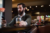 Homme utilisant un téléphone portable tout en étant assis dans le bar — Photo de stock