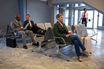 Женщина сидит с багажом в зоне ожидания в терминале аэропорта — стоковое фото