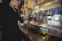 Garçonete limpando máquina de café expresso com guardanapo no café — Fotografia de Stock