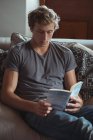 Uomo seduto sul divano a leggere un libro in salotto — Foto stock