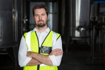 Портрет чоловіка-працівника з обіймами, що стоять на заводі — стокове фото