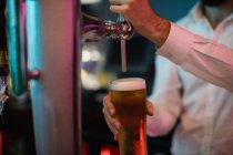 Close-up de bartender enchimento de cerveja da bomba de bar no balcão de bar — Fotografia de Stock