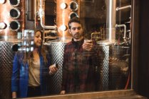 Homem e mulher examinando garrafas na fábrica de cerveja — Fotografia de Stock