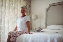 Портрет старшого жінка, сидячи на ліжку в спальні в домашніх умовах — стокове фото