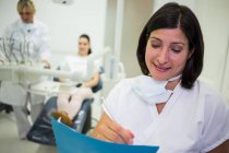Female dentist writing report in dental clinic — Stock Photo