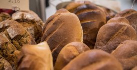 Pan Einkorn y pan de masa fermentada se mantienen juntos en el mostrador de la panadería en el supermercado - foto de stock