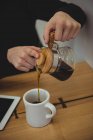 Mann gießt Kaffee aus Kaffeekessel in Kaffeebecher im Café — Stockfoto