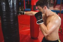Boxer punching boxing bag in fitness studio — Stock Photo