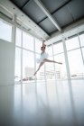 Балерина практикует балет в студии с окнами — стоковое фото