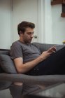 Чоловік використовує мобільний телефон на дивані вдома — стокове фото