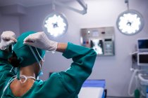 Visão traseira do cirurgião feminino usando máscara cirúrgica no teatro de operação do hospital — Fotografia de Stock