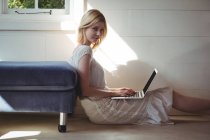 Retrato de mulher bonita usando laptop na sala de estar em casa — Fotografia de Stock