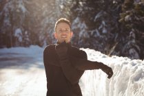 Чоловік розтягує руки в лісі взимку — стокове фото