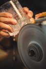 Close-up of glassblower polishing and grinding a glassware at glassblowing factory — Stock Photo